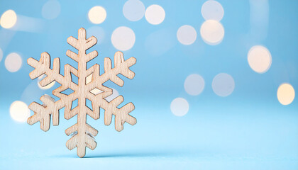 Wooden snowflake ornament on softly blurred blue background, festive winter holiday, Christmas