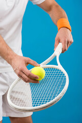 A tennis player holds a racket and a ball on a solid blue background, ready to serve