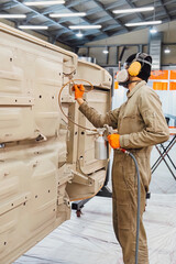 Specialist spraying anti rust sealant into the hidden chassis cavities. Protection against corrosion and internal body element sealing in a professional auto service shop