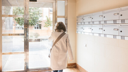 Woman leaving apartment building lobby through glass door