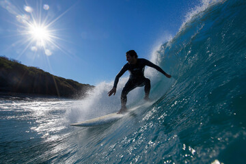 A dynamic shot of a surfer expertly navigating a powerful wave, highlighted by brilliant sunlight, capturing the thrill and excitement of surfing and ocean life.