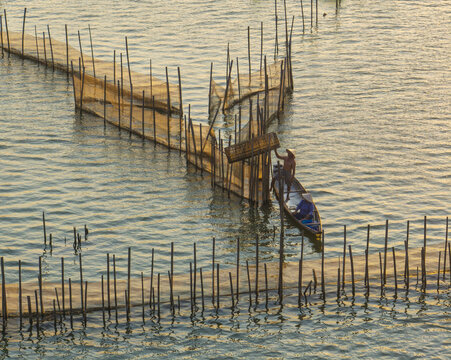Aerial view of a lone fisherman navigates his small boat through a maze of wooden stakes and nets on the tranquil lake,Chuon lagoon, Hue Province, Vietnam