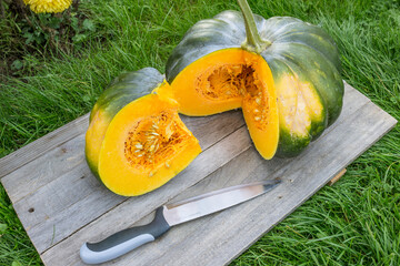 A cut pumpkin with a knife lying nearby