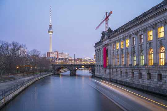 View of the iconic Fernsehturm tower rising above the Spree river, a red crane standing tall next to the Bode Museum, Berlin, Berlin, Germany.