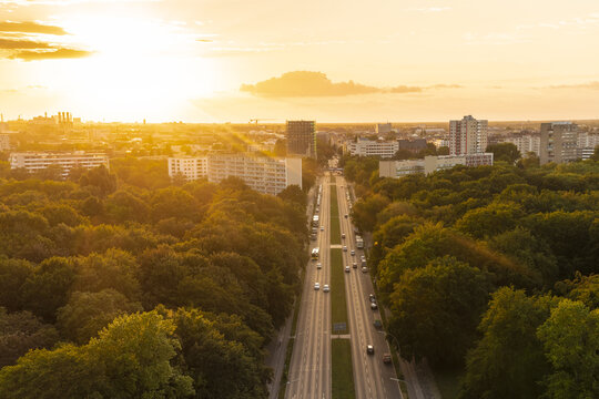 View of sunlight piercing through the trees and illuminating the 17. Juni road, casting a golden hue over the city's skyline, Tiergarten, Berlin, Germany.