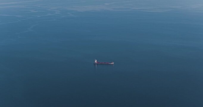 Aerial view of a lone ship sailing on the tranquil, deep blue sea, a mesmerizing contrast of industrial presence and nature's serenity, Erchie, Amalfi Coast, Italy.