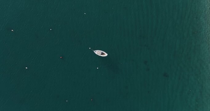 Aerial view of a single boat floating on the dark teal water, creating a striking contrast, Erchie, Amalfi Coast, Italy.