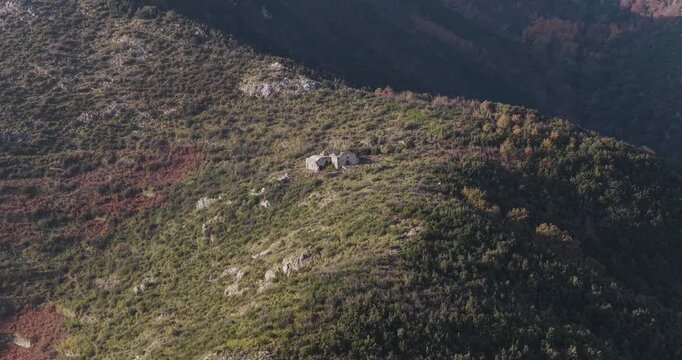 Aerial view of a small stone building perched atop a hill, surrounded by earthy tones of the landscape, Erchie, Amalfi Coast, Italy.