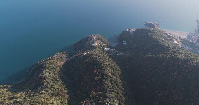 Aerial view of the winding roads and lush green hills meeting the blue sea along the Erchie coastline, a scenic landscape, Erchie, Amalfi Coast, Italy.