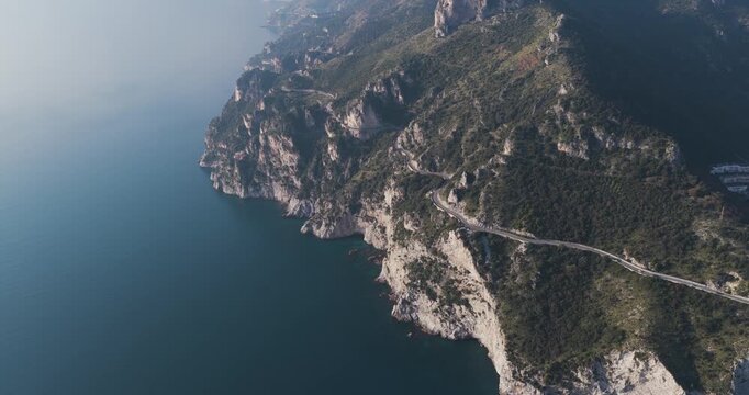 Aerial view of the dramatic cliffs meeting the deep blue sea, a winding road hugging the coastline, Erchie, Amalfi Coast, Italy.