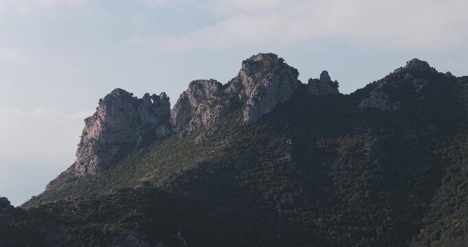 Aerial view of jagged peaks rising sharply, their rocky faces contrasting with the deep green vegetation clinging to their slopes, Erchie, Amalfi Coast, Italy.