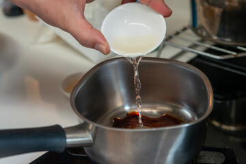 鍋に調味料を加える調理工程のクローズアップ