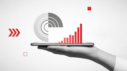 A hand holding a tablet with a red bar graph on the screen and various symbols around it on a grey background