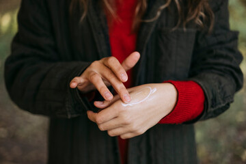 Person applying nourishing hand cream to protect skin from dryness.