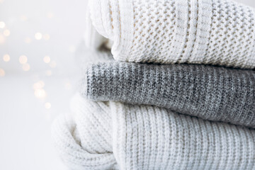 Close-up of white and gray sweaters with festive bokeh lights.
