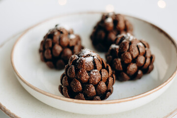 Artisanal chocolate pine cone dessert on rustic ceramic plate.