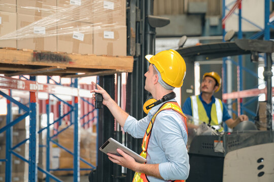 Smart caucasian warehouse man,manager use digital tablet check package with worker forklift driver loading box on shelf, product distribution inventory management, Logistics shipping business planning