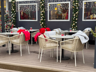 Outdoor cafe terrace decorated for Christmas with blankets and lights. Winter leisure space, seasonal hospitality and festive urban atmosphere