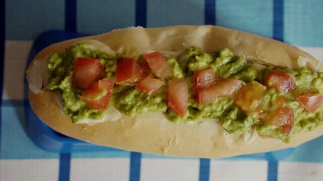 Authentic South American Street Food: Completo Italiano Side View, Overloaded Chilean Completo Hot Dog with Extreme Mayonnaise and Avocado