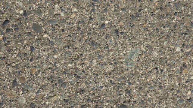 Close-Up of Exposed Aggregate Concrete and Rough Pavement Surface Texture, Construction Material Background Video: Concrete with Embedded Stones and Rock Fragments