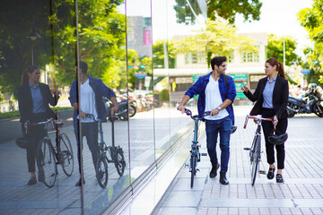 Urban professionals walking with bicycles in modern city environment.