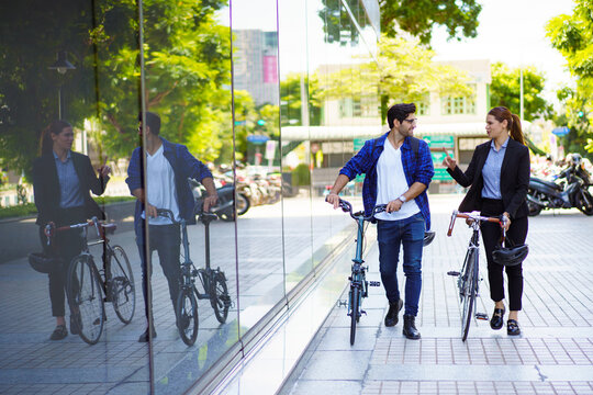 Urban professionals walking with bicycles in modern city environment.
