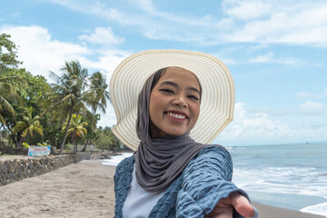 a woman wearing a hijab is on holiday at the beach