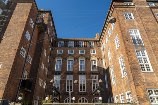 View of striking brick facades rise high under a clear blue sky, showcasing architectural details and symmetrical window arrangements, Indre By, Denmark.