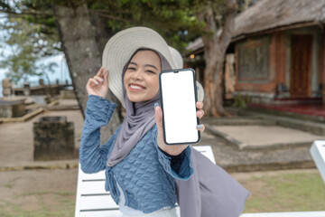 a young woman holding a cell phone in a hotel with a beach view while on vacation, perfect for vacation promotions and social media, holiday season.