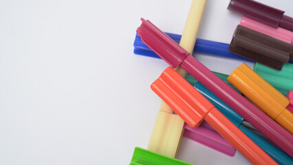 Close up of various multi colored markers scattered randomly on a white background, useful for stationery and education themes