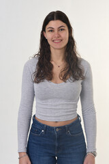 Naklejka premium waist up front view portrait of an 18-year-old girl, looking at the camera and smiling with teeth on a white background.