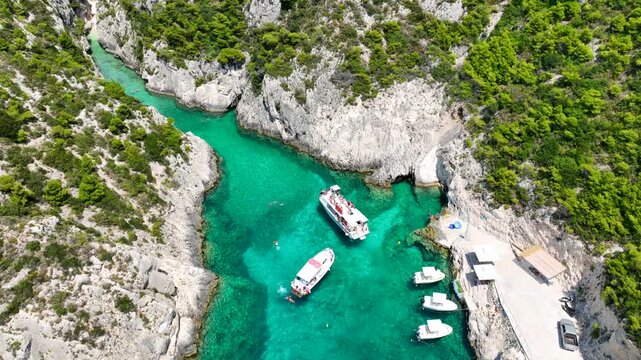 Aerial drone video of of Porto Stenitis famous fjord shaped bay with crystal clear turquoise sea and small beach  ideal for snorkeling visited by small tourist boats, Zakinthos island, Ionian, Greece