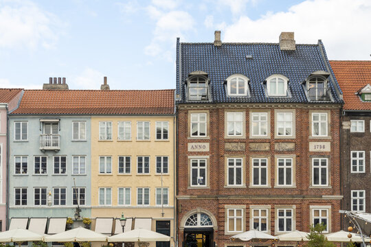 View of colourful facades of historic buildings standing shoulder-to-shoulder under a bright sky, reflecting the charm of a waterside district, Nyhavn, Copenhagen, Denmark.