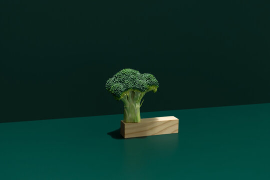 Florete fresco de br&oacute;coli colocado sobre piezas de madera sobre fondo verde oscuro	