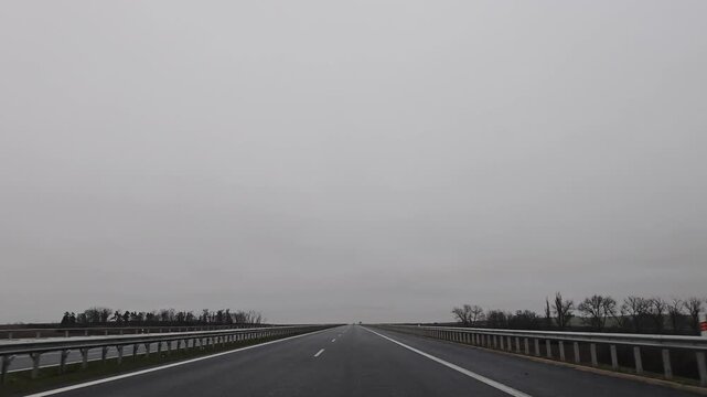 Driving on a highway from Karlovy Vary to Prague during winter, surrounded by a bleak, overcast landscape and patches of snow along the roadside.