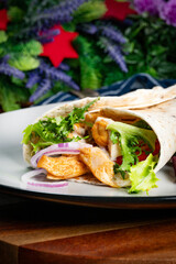Wholegrain tortilla wraps with vegetables and chicken on a plate.