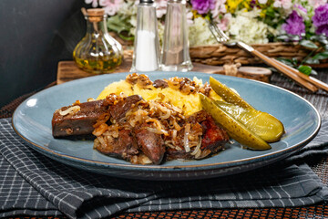 Turkey liver with mashed potato and pickled cucumber.