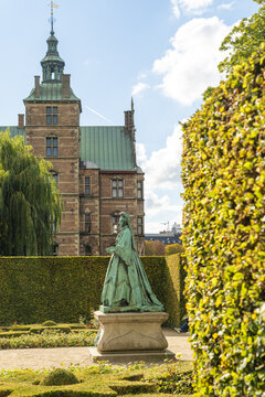 View of Queen Caroline Amalie by Vilhelm Bissen statue of a regal figure stands in the foreground, with Rosenborg Castle's aged brick, Copenhagen, Rosenborg Castle, Denmark.