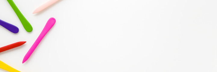 Colorful wax crayons on light gray table background. Closeup. Wide banner. Empty place for text. Top down view.