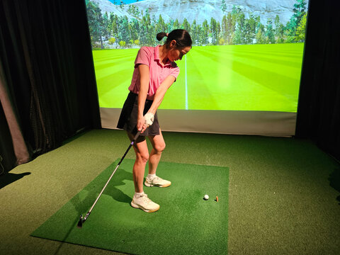Golf player swings club in indoor golf simulator at local sports facility during afternoon session concept