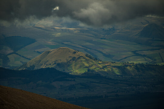 View of a sun-drenched mountain ridge, its slopes painted with shadows under a brooding sky, a tranquil scene, Latacunga, Cotopaxi, Ecuador.