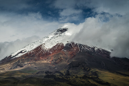 View of a snow-capped volcano rises majestically, its peak shrouded in ethereal clouds, painted with hues of grey and white, Cotopaxi, Latacunga, Cotopaxi, Ecuador.
