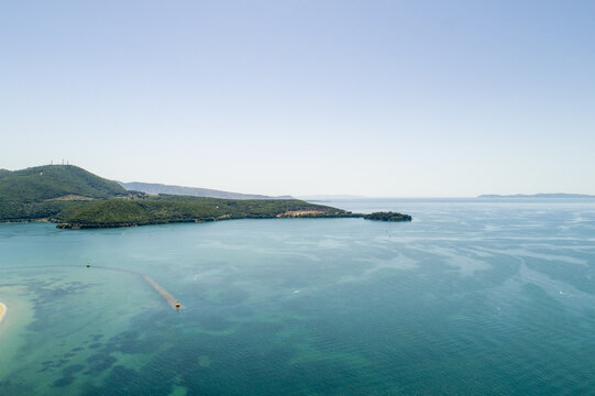 Aerial view of turquoise waters meeting verdant hills under a boundless sky, Igoumenitsa, Thesprotia, Greece.