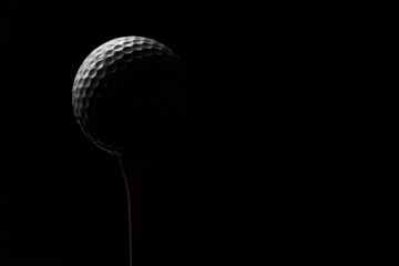 Golf ball on a tee on a black background close-up