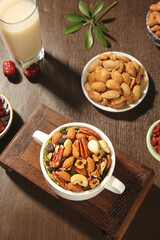 Mixed nuts dried fruits cashews healthy snack variety with milk on wooden table daily nutrition concept