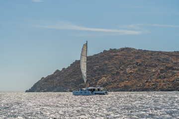 Sailboat sailing near Delos island with rocky coastline Greece © Juan