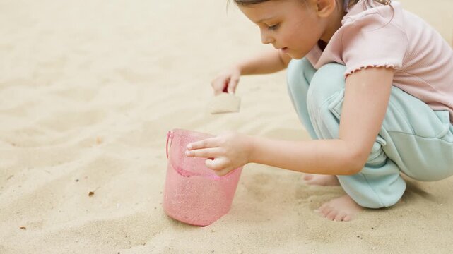 A girl plays in a sandbox on a playground in a park