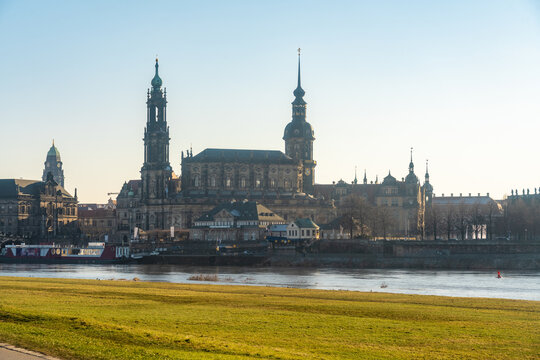 View of the majestic Cathedral St. Trinitatis architecture reflected in the river, with the old buildings standing tall against a clear blue sky, Dresden, Saxony, Germany.
