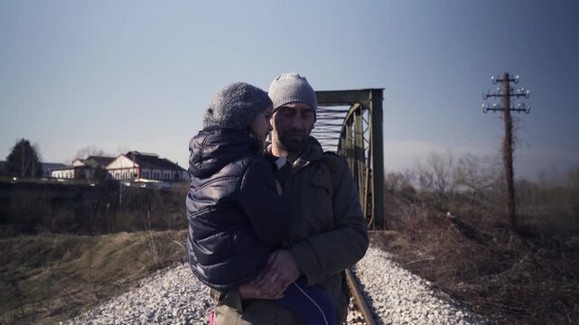 Portrait of an immigrant father while carrying a little cute daughter in his arms on their travel in transit into a better tomorrow, steady tracking shot