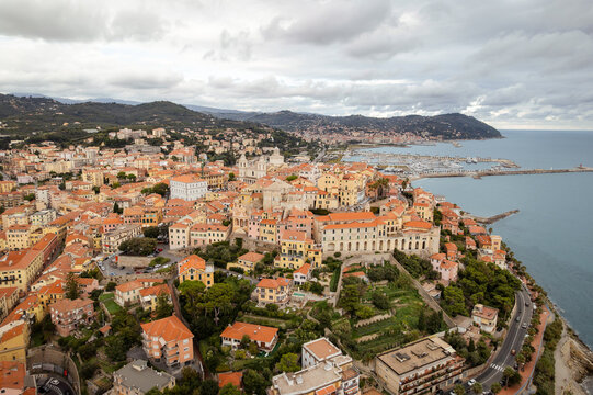 Aerial view of terracotta rooftops cascading down to the azure sea, bordered by the elegant architecture of Imperia, Liguria, Italy.